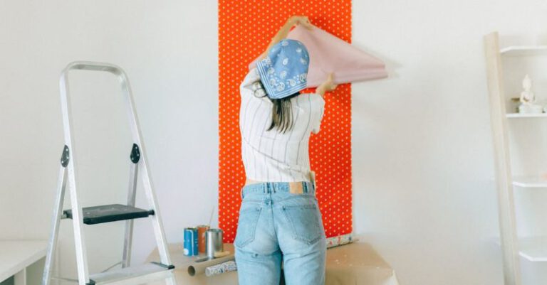 Wallpaper Makeovers - Back View of a Woman Putting Up a Wallpaper on the Wall