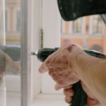 Cordless Drills - Crop man screwing metal detail on window