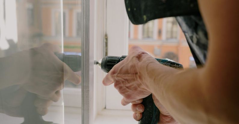 Cordless Drills - Crop man screwing metal detail on window