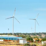 Sustainable Building Materials - Scenic view of wind turbines against houses under cloudy blue sky in countryside in daytime