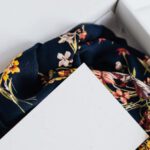 Custom Storage - From above of stylish black silk floral pattern cloth with white visit card mockup placed in white carton box after receiving postal delivery of online order