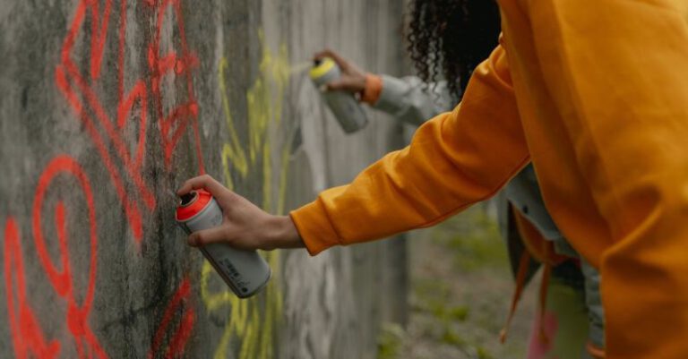 Paint - A Person in Yellow Long Sleeve Shirt Spray Painting a Wall