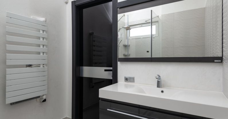 Heated Flooring - Creative design of bathroom with door between heated towel rail and washstand under rectangular mirror in light house